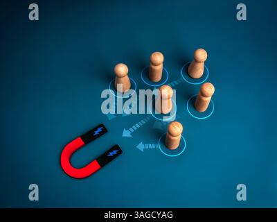 Marketing digitale, target di pubblico, attrarre lead e concept dei clienti. Simboli umani in legno attratti dal magnete a ferro di cavallo con frecce sul dorso blu Foto Stock