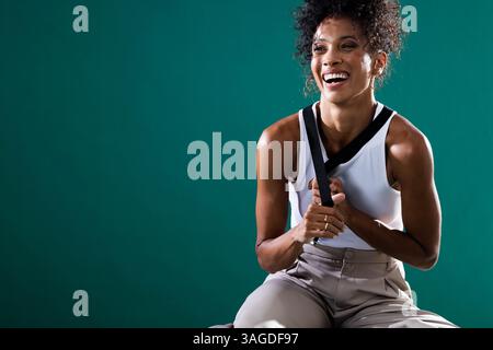 Donna sorridente in un outfit casual che regge le bretelle, esprimendo gioia e sicurezza. Moda, trendy, sicuro di sé, felicità, allegro, positivo Foto Stock