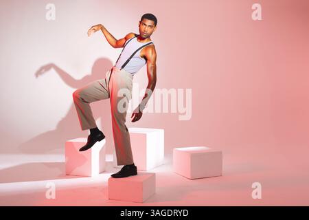 Uomo afro-americano che posa elegantemente in studio indossando bretelle e pantaloni. Moda, stile, fiducia, trendy, abbigliamento, maschio Foto Stock