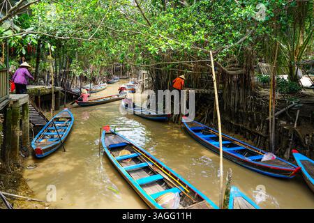 Long An province, Vietnam - 15 marzo 2025: Barche a remi in legno sui corsi d'acqua del delta del Mekong Foto Stock