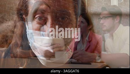 Giovani professionisti che collaborano a progetti in ufficio, indossando maschere per la sicurezza Foto Stock