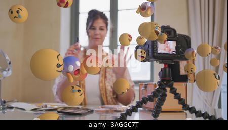 Immagine di icone emoji su vlogger femminile nel visualizzatore di telecamere che registra vlog a casa Foto Stock