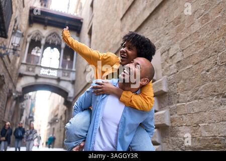 Coppia di turisti che si diverte a fare il piggyback a barcellona, quartiere gotico, spagna Foto Stock