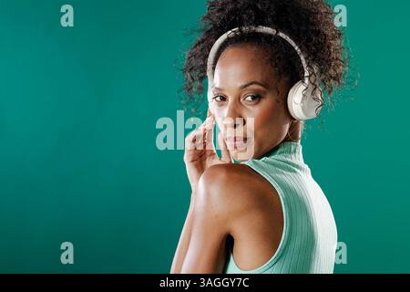 Donna afroamericana che indossa le cuffie che ascolta la musica e che sembra sicura di sé. stile di vita, tecnologia, sicurezza, relax, divertimento Foto Stock