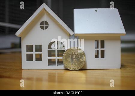 bitcoin di fronte a due case, concetto, investire in bitcoin o in stato reale Foto Stock