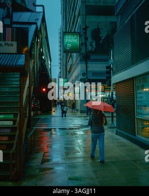 Persona che cammina con un ombrello rosso in una notte di pioggia a Chicago, Illinois Foto Stock