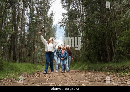 Famiglia che cammina lungo un sentiero nel bosco scattando un selfie con un bastone per selfie Foto Stock