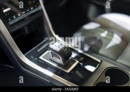 primo piano di una moderna manopola del cambio automatico in una console per auto lucida, che mette in risalto praticità, stile e design automobilistico degli interni. Foto Stock