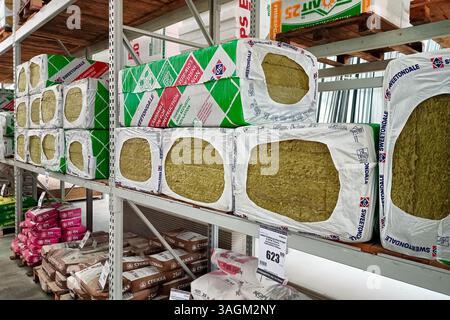 Pile di materiali isolanti confezionati disposte in modo ordinato su scaffali di stoccaggio in un magazzino o in un negozio, con materiali edili. Vari prodotti Foto Stock
