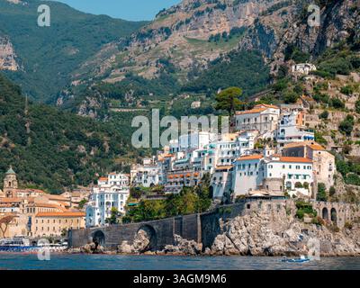 Villaggio collinare della Costiera Amalfitana con edifici storici e sfondo montano visto dal Mar Mediterraneo, Italia Foto Stock