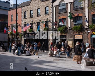 Gruppi di persone che si godono il sole al Temple Bar nella città di Dublino, Irlanda. Foto Stock