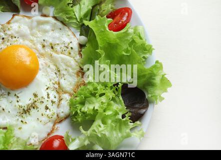 Un unico uovo fritto e verdure isolate su fondo bianco. Concetto di cibo sano. Direttamente sopra. Foto Stock