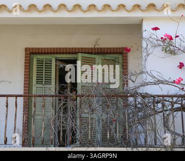Vecchia casa cipriota abbandonata con balcone, fiori e tende di Bougainvillea a Varosha, Famagosta, Cipro del Nord Foto Stock