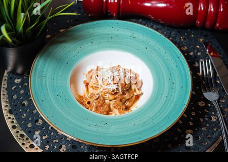 Tagliatelle preparate al momento servite con salsa ragù di carne e formaggio grattugiato su un piatto decorativo, in stile cucina italiana. Foto Stock
