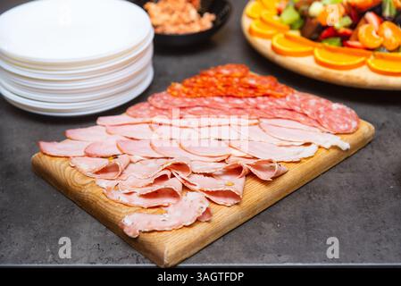 Tavola di legno con un assortimento di affettati, tra cui salame, prosciutto e mortadella, ideale per antipasti o buffet. Foto Stock