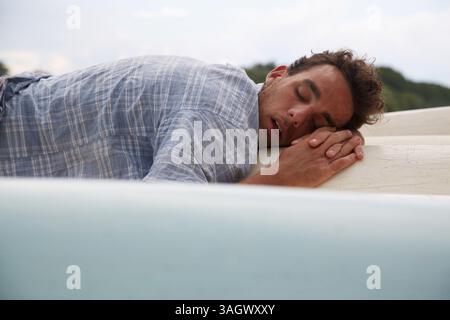 Uomo che dorme sul fondo delle canoe Foto Stock