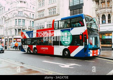 London Open Top TOOTBus per i turisti che visitano autobus all'aperto dipinti della bandiera del Regno Unito su London Street, trasporti pubblici a basse emissioni Foto Stock