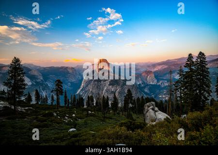 Una vista di un Half Dome illuminato dal tramonto rosa dal Glacier Point nel Parco Nazionale di Yosemite durante l'estate Foto Stock