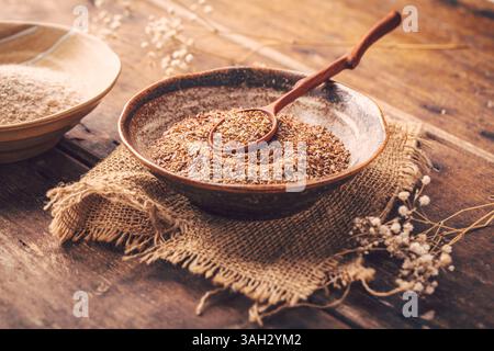 Semi di lino tritati e un mucchio di buccia di psico (Isabgol) in una ciotola su un tavolo di legno Foto Stock