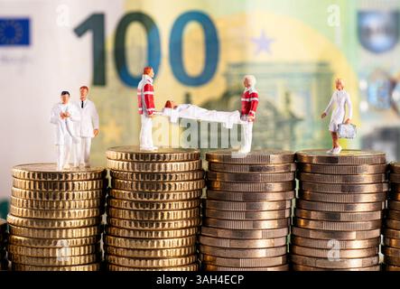 Foto simbolica con figure del settore sanitario su pile di denaro davanti a un banconota da cento euro Foto Stock