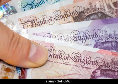 Sterline britanniche tenute in mano, macro primo piano, iscrizione della Banca d'Inghilterra Foto Stock
