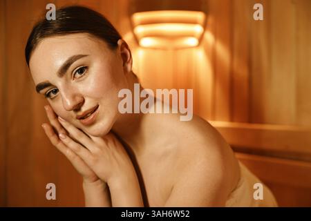 Bella giovane donna che si rilassa nella sauna calda Foto Stock