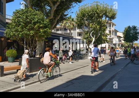 Persone in bicicletta e a piedi nel centro della rinomata località turistica sulla costa della Versilia in estate, forte dei Marmi (Lucca), Toscana, Italia Foto Stock