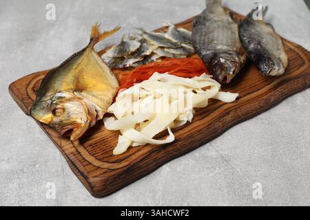 Molti diversi spuntini di pesce secco sul tavolo grigio chiaro, primo piano Foto Stock