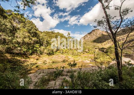 Tranquillo piccolo lago nella campagna brasiliana, con vegetazione lussureggiante e sponde sabbiose intorno ad esso, in una giornata di sole e luce. Foto Stock