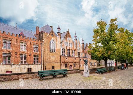 Bruges, Belgio - 09-27-2024:: Case medievali sul canale a Bruges (Bruges), Belgio. Statua di Frank Van Acker Foto Stock