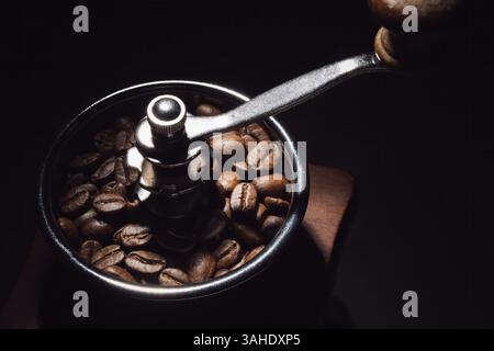 foto ravvicinata dei chicchi di caffè in una macchina per macinacaffè manuale con sfondo scuro Foto Stock