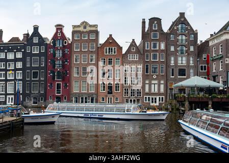 Le barche turistiche dei canali si trovano sull'acqua e riflettono le colorate case olandesi di amsterdam, paesi bassi Foto Stock
