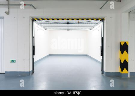 Garage sotterraneo vuoto con porta aperta e illuminazione luminosa in un moderno edificio di appartamenti Foto Stock