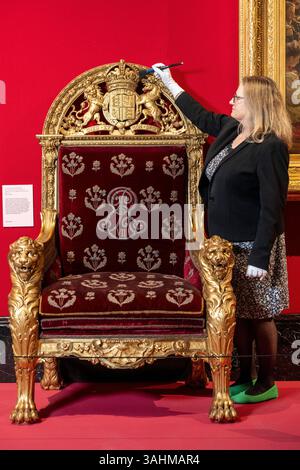 Londra, Regno Unito. 10 aprile 2025. Un membro dello staff con la sedia del trono di re Edoardo VII, 1901-2, in anteprima di The Edwardians: Age of Elegance alla King's Gallery, Buckingham Palace. La mostra esplora le vite e i gusti di due delle coppie reali britanniche, re Edoardo VII e regina Alessandra, e re Giorgio V e la regina Maria, e si svolge dall'11 aprile al 23 novembre 2025. [Utilizzo - notizie solo per scopi editoriali in relazione alla mostra] crediti: Stephen Chung / Alamy Live News Foto Stock