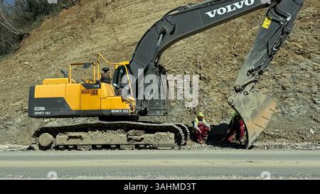 Budva, Montenegro - 9 aprile 2025: Riparazione della strada Budva - Tivat. I lavoratori riposano vicino all'escavatore. Foto di alta qualità Foto Stock