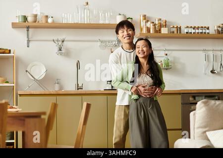 Una giovane coppia felice condivide un caldo momento di colazione nella loro moderna cucina casalinga, sorridendo gioiosamente. Foto Stock