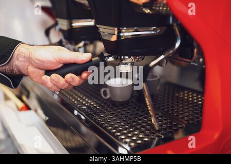 Primo piano di un barista professionista che utilizza la macchina per caffè espresso. Foto Stock