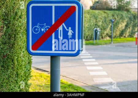 Un segnale blu con una linea diagonale rossa indica la fine di un percorso condiviso per pedoni e ciclisti, segnando il passaggio a una zona stradale diversa. Foto Stock