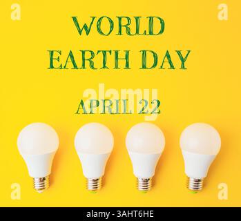 Quattro lampadine su sfondo giallo con sopra le parole della giornata Mondiale della Terra. Concetto di consapevolezza ambientale. conce per le vacanze di giorno della terra Foto Stock