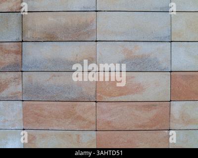 Parete in mattoni di colore marrone e grigio. La parete è fatta di mattoni e ha una consistenza ruvida Foto Stock