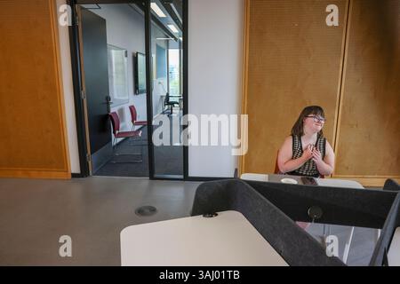 Donna con la sindrome di Down seduta in ufficio Foto Stock