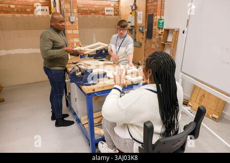 Uomini e donne disabili che lavorano in officina Foto Stock