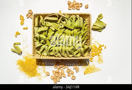 Tagliatelle di spinaci e pasta cruda assortita su sfondo bianco Foto Stock