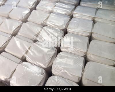 File di confezioni bianche sono impilate saldamente in un magazzino, circondate da un ambiente pulito e organizzato. Foto Stock