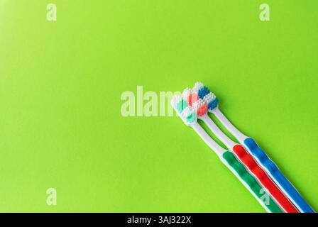 Tre spazzolini multicolore su sfondo verde chiaro. Concetto di igiene orale Foto Stock