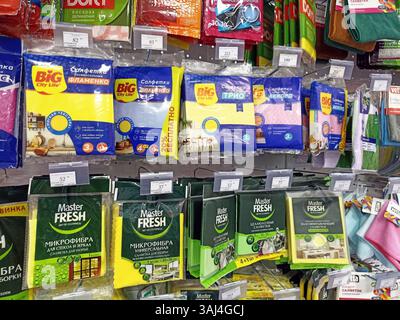 Espositore dei materiali di pulizia con vari prodotti in spugna e panno sugli scaffali dei negozi. Foto Stock