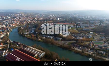 Immagine drone di Montbeliard, Francia, che mostra il tortuoso fiume Allan, i quartieri residenziali, le zone industriali e le colline circostanti. Un mix equilibrato di natura, storia e vita moderna. Foto Stock