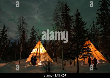 L'aurora boreale (Aurora Boreale) sopra i tepee illuminati nelle foreste vicino a Yellowknife, territori del Nord-Ovest, Canada Foto Stock