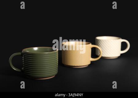 Tazze in ceramica diverse su sfondo nero Foto Stock