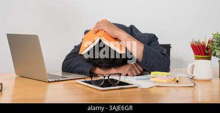 Ragazzo affaticato che dorme durante i suoi studi al caffè della città, gli mette un libro sulla testa, stanco di fare compiti a casa. Lavoro fino a tardi in ufficio. Stresse Foto Stock
